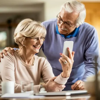 square-happy-senior-woman-using-cell-phone-with-her-husband-home